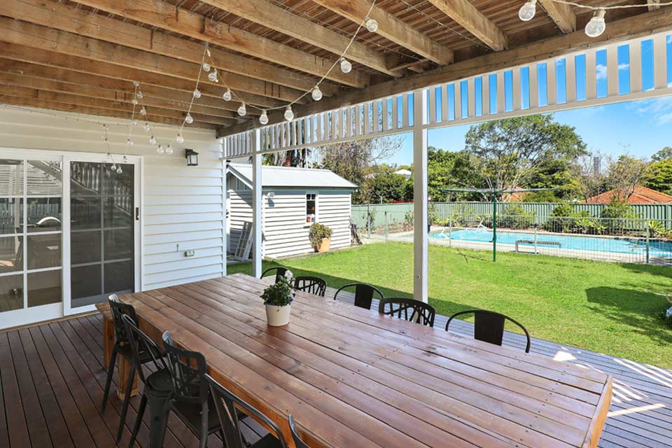 Backyard patio with large dining room table, lights, and swimming pool